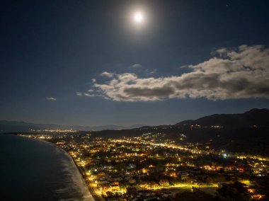 Korfu 'daki Acharavi Sahil Kasabası' nın Hava Gecesi Manzarası Dolunay ve Long Beach üzerindeki Bulutlar, Aydınlanmış Sahil Resort ve Köy Işıkları