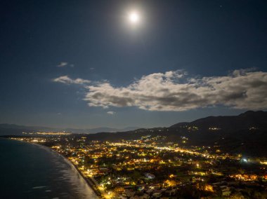 Korfu 'daki Acharavi Sahil Kasabası' nın Hava Gecesi Manzarası Dolunay ve Long Beach üzerindeki Bulutlar, Aydınlanmış Sahil Resort ve Köy Işıkları