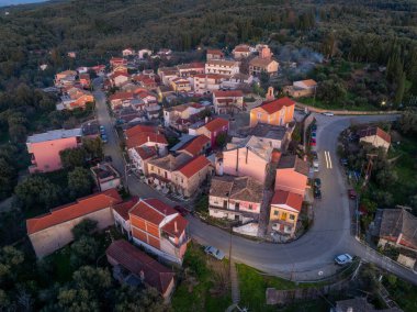 Xanthates köyü Korfu Yunanistan 'ın merkez meydanı ve kilisesinin hava manzarası, alacakaranlıkta geleneksel evler ve kiremitli çatılarla aydınlandı.