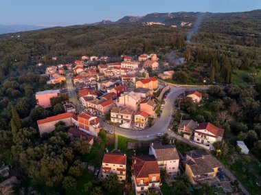 Korfu 'daki Xanthates köyünün geniş hava drone görüntüsü güneş batarken selvi ve zeytin ağaçlarıyla çevrili Yunanistan