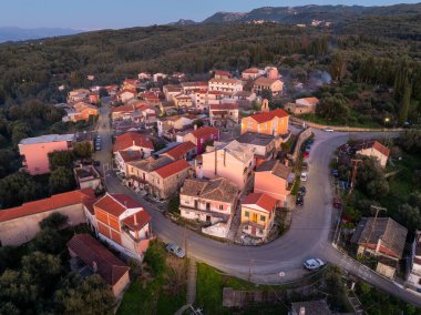 Korfu 'da geleneksel Xanthates yerleşiminin panoramik hava manzarası gün batımında dağları olan zeytin koruluklarında yuva yapmış Yunanistan