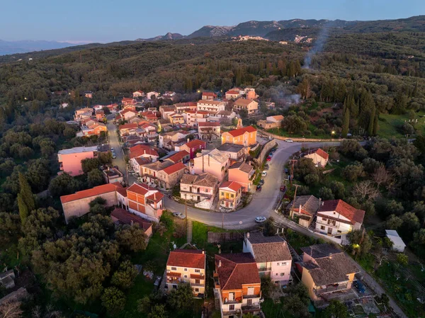 Korfu 'daki Xanthates köyünün geniş hava drone görüntüsü güneş batarken selvi ve zeytin ağaçlarıyla çevrili Yunanistan