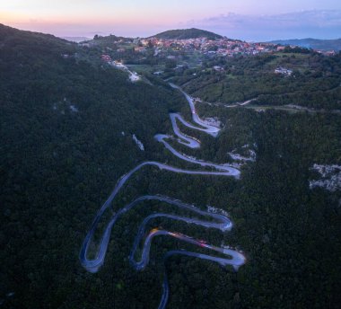 Alacakaranlıkta aydınlanan Sokraki köyüne giden yılanımsı dağ yolunun renkli gökyüzü, Korfu adası, Yunanistan