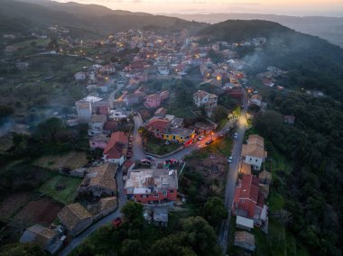 Sokraki köyünün panoramik hava günbatımı manzarası bacalardan yükselen dumanla, Korfu adası, Yunanistan
