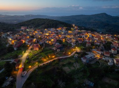 Günbatımında Sokraki dağ köyünün renkli gökyüzü ve Korfu adasında yeşil tepelerle çekilmiş panoramik insansız hava aracı görüntüleri