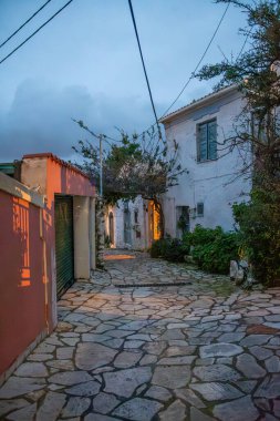 Taş kaldırımlar, geleneksel beyaz duvarlar, renkli günbatımı gölgeleri ve Korfu 'daki elektrik kablolarıyla...