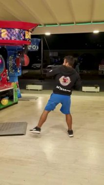 Geceleyin lunaparkta ya da panayırda Güç Testi yapmak için Boks Atari Makinası Oyunu Yumruklayan Genç Adam