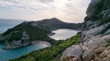 Porto Timoni 'nin Corfu Yunanistan' daki çifte kumsalı, turkuaz sular ve güneşli bir öğleden sonra yemyeşil tepeler, ünlü İyon adası