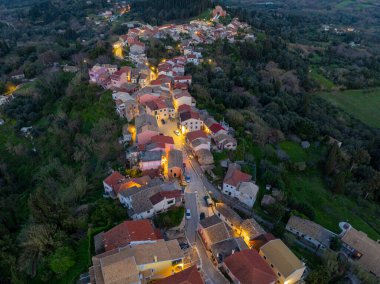 Vertical aerial drone view following the main street of Agrafoi village in Corfu Greece showing glowing streetlights and village density