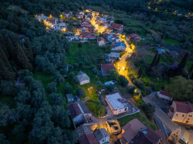 Kuzey Korfu Yunanistan 'daki geleneksel Klimatia köyünün mavi saat alacakaranlığı sırasında aydınlık sokakları ve kırmızı çatıları ile hava manzarası