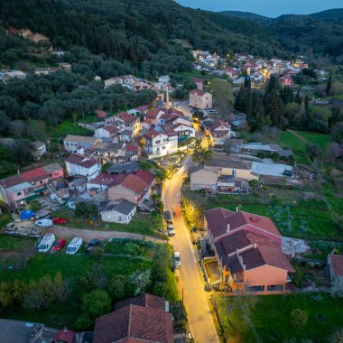 Korfu Yunanistan 'ın Klimatia köyü merkezinin hava perspektifinde kilise çan kulesi ve alacakaranlıkta rahat bir mahalle yer alıyor
