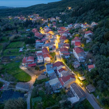 Korfu 'daki Klimatia köyünün yüksek açılı görüntüsü ana yolun akşam karanlığında geleneksel mimariden geçtiğini gösteriyor.