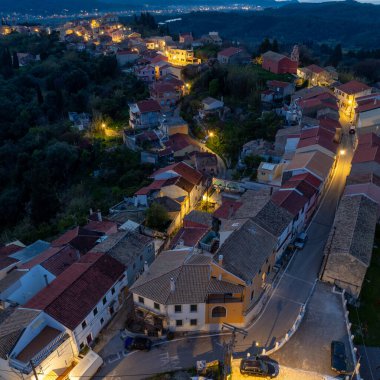 Geceleri Agrafoi köyü Korfu Yunanistan 'daki geleneksel evlerin yüksek açılı manzarası, aydınlık dar sokaklar ve akşamları terasotta çatıları