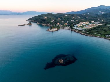 Günbatımında Agios Spiridon sahil beldesi ve batımındaki resifin insansız hava aracı görüntüsü Korfu Adası Yunanistan