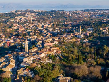 Yunanistan 'ın Corfu adasında günbatımında uzak Eski Kale ve deniz kıyısına sahip geleneksel Potamos köyünün panoramik hava manzarası, güzel yaz manzarası.