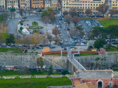 Yunanistan 'ın Eski Korfu Kalesi' ne giden köprünün manzarası, şehir binaları ve otoparklarla dolu..