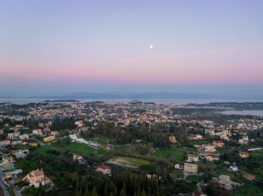 : Korfu kasabasının ve Eski Kale 'nin havadan panoramik manzarası. Alacakaranlıkta dolunay İyon denizi ve pembe gökyüzü üzerinde yükseliyor.
