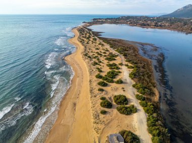 Korission Gölü 'nü İyon Denizi' nden ayıran Halikounas Sahili 'nin dikey insansız hava aracı görüntüsü, Yunanistan' ın Korfu adasındaki ünlü kumlu kıyı şeridi ve vahşi doğa manzarası