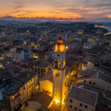 Yunanistan 'ın Kerkyra kentindeki Corfu Town' da gün batımında gökyüzüne bakan Aziz Spyridon Kilisesi çan kulesinin hava görüntüsü. Renkli turuncu bulutları olan tarihi dini simgelerin silueti..