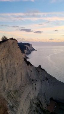 Gün batımında sakin sulara bakan kayalıklar