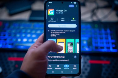 Arama motoru ve internet tarayıcı konsepti için arka plan mavi klavye arka planına sahip Play Store ekranında Google Go uygulamasını gösteren akıllı telefonu tutan kişi