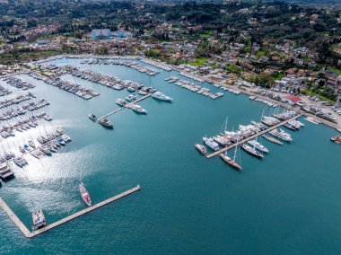 Yunanistan 'ın Corfu Adası' ndaki Gouvia Limanı 'na yanaşan lüks yat ve yelkenlilerin insansız hava aracı görüntüsü; güneşli bir günde İyon Denizi' nde pitoresk bir Akdeniz limanı ve deniz turizm merkezi..