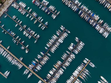 Yunanistan Korfu adasında demirlemiş yatları ve yelkenli tekneleriyle Gouvia Marina 'nın hava manzarası güneşli bir yaz günü İyon Denizi' nde lüks bir seyahat noktası, limanın insansız hava aracı görüntüleri.