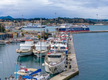 Beyaz Yolcu Feribotları ve Seyahat Gemileri, güneşli bir günde Korfu Kasabası Liman Terminali 'ne tarihi kale geçmişiyle kenetlendi.