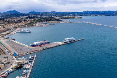 Yunanistan 'da bulutlu bir günde, iskeleye demirlemiş feribot, mavi İyon denizi ve dağ manzaralı Korfu Kerkyra Limanı' nın hava manzarası