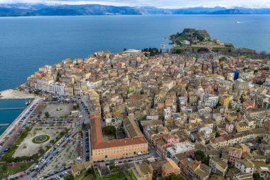 Yunanistan 'ın Kerkyra kentindeki Korfu Eski Kasabası' nın hava manzarasında tarihi Eski Kale, Venedik mimarisi, Spianada Meydanı ve bulutlu bir UNESCO dünya mirası altındaki manzaralı İyon Denizi kıyı şeridi yer alıyor.