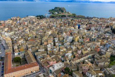 Yüksek açılı insansız hava aracı Corfu Eski Kasabası 'nın yoğun renkli binalarına bakarak tarihi Eski Kale ve mavi denize doğru yol alıyor.