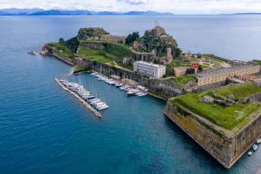 Yunanistan 'ın Kerkyra kentindeki Eski Korfu Kalesi' nin hava manzarasında Venedik taş tahkimatları, yelkenli Mandraki marinası ve Arnavutluk 'un tarihi UNESCO Dünya Mirası Sahası manzarası yer alıyor.