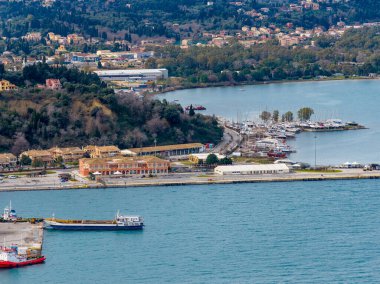 Yunanistan 'ın Corfu Town kentindeki eski kalenin eteğindeki sahil mimarisi ve Mandraki limanı. İyon Denizi 'ndeki Geleneksel Yapı ve Teknelerin Resimli Manzarası, UNESCO Dünya Mirası Sitesi