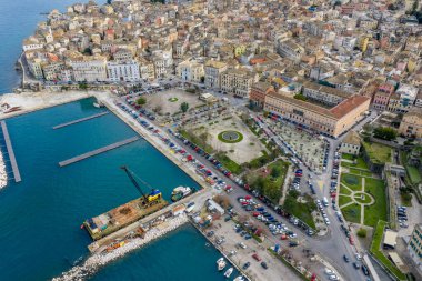 Korfu Kasabası 'ndaki Eski Liman Meydanı ve Tarihi Mimarinin Hava Görüntüsü (Kerkyra): Geleneksel Binalarla Panoramik Manzara, Spilia Kışlası, Liman Altyapısı ve İyon Denizi Kıyısındaki İnşaat Turna Mavnası