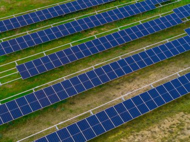 Yeşil alan üzerindeki büyük güneş panelinin hava aracı görüntüsü, fotovoltaik güç istasyonu temiz yenilenebilir elektrik üreten, sürdürülebilir enerji altyapısı, yukarıdan modern güneş çiftliği deseni