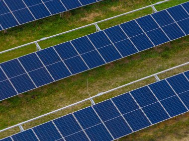 Modern bir fotovoltaik çiftlikteki güneş paneli sıralarının havadan görünüşü, geniş mavi güneş pili panelleri ile sürdürülebilir yeşil enerji üretimi çimen alanı, alternatif yenilenebilir enerji istasyonu