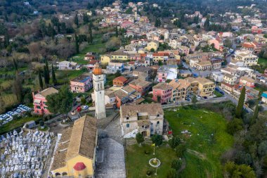Potamos köyünün merkezindeki tarihi kilise kulesi ve mezarlığın insansız hava aracı görüntüsü Korfu Yunanistan geleneksel hava manzarası