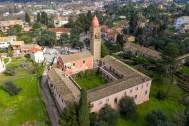 Yunanistan 'ın Korfu kentindeki Kompitsi köyünün hava manzarası. Terracotta çatıları, yemyeşil tepeleri ve parlak yaz güneşi altında selvi ağaçları olan geleneksel Akdeniz manzarası