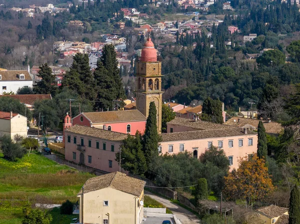 Yunanistan 'ın Korfu Adası' ndaki selvi ağaçlarıyla çevrili Kompitsi köyündeki tarihi kırmızı kubbeli kilise kulesi ve çan kulesinin telefoto görüntüsü.