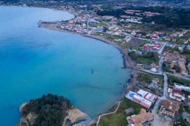 Sidari kıyı beldesi Korfu 'nun insansız hava aracı görüntüsü: Geleneksel mimari, turkuaz deniz suları, kumlu plajlar ve gündüz gözüyle lüks sahil villaları ile Akdeniz manzaralı Akdeniz kasabası.