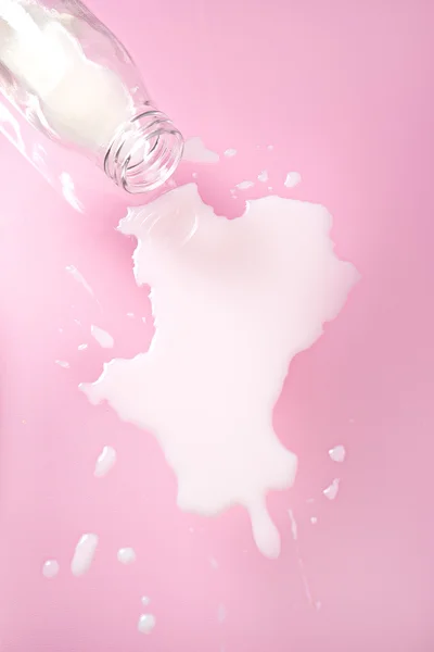 Latte versato su sfondo rosa — Foto Stock