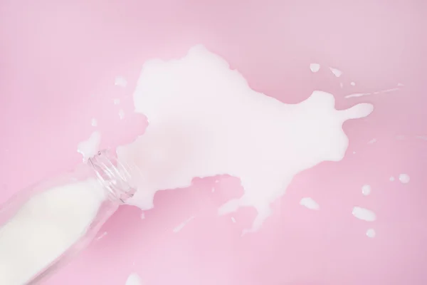 Pembe bir arka plan üzerinde dökülen süt — Stok fotoğraf