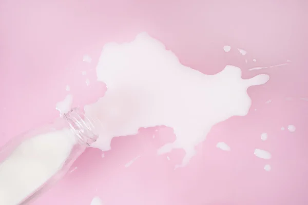 Leche derramada sobre fondo rosa —  Fotos de Stock