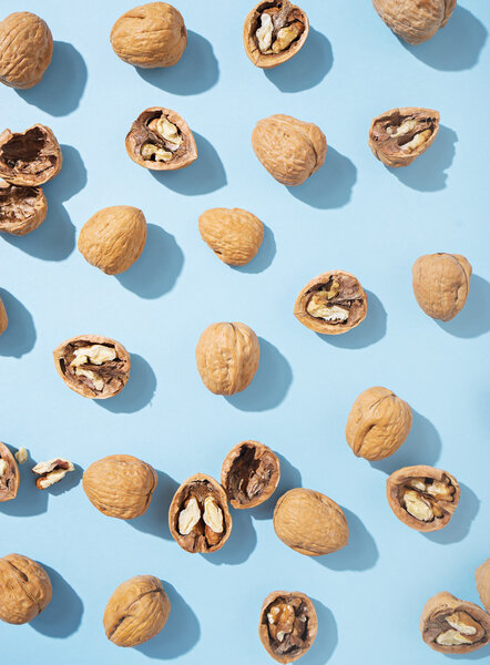 Walnuts whole in their skins, chopped on blue background