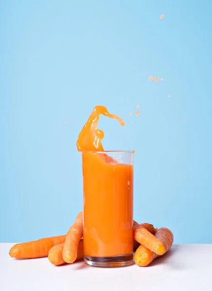 Colorful fresh carrot juice splash in glass — Stock Photo, Image