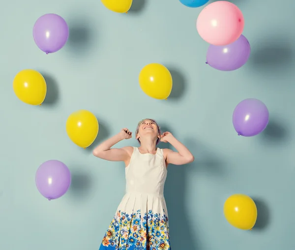 Flicka ha kul med färgade ballonger på blå bakgrund — Stockfoto