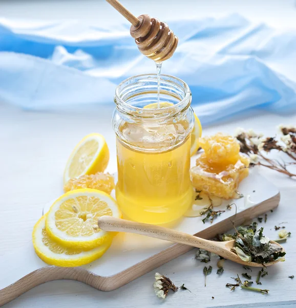 Miel en tarro con cazo de miel, limón y té —  Fotos de Stock