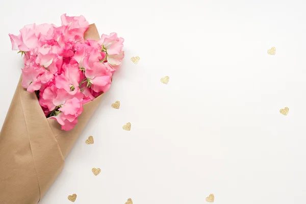 Nové růžové květy s papírové srdce na stole — Stock fotografie