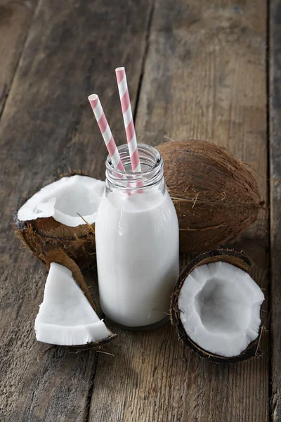 Kokosnüsse mit Kokosmilch auf Holztisch — Stockfoto