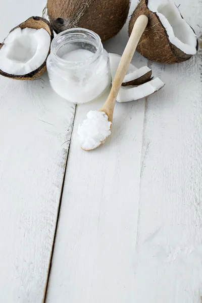 Coco com óleo de coco sobre mesa branca — Fotografia de Stock